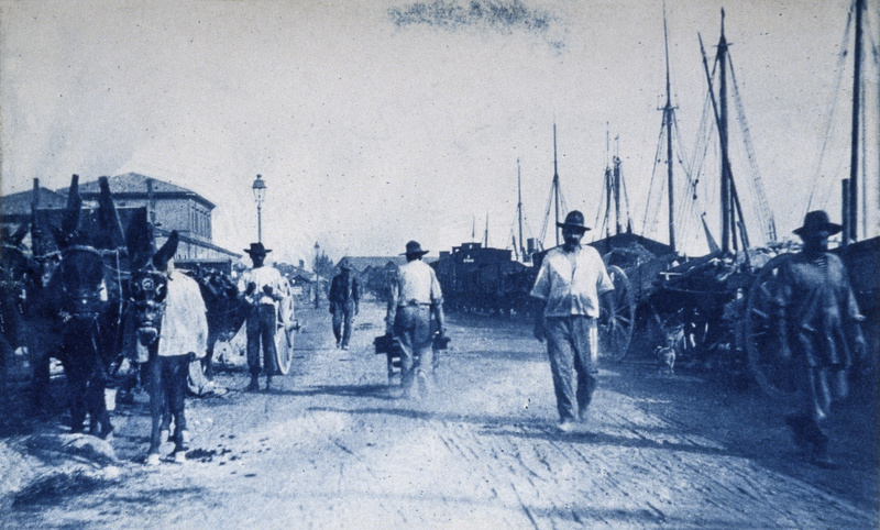 Men at work in the Darsena, on the right the freight train and carriages, while on the left the customs